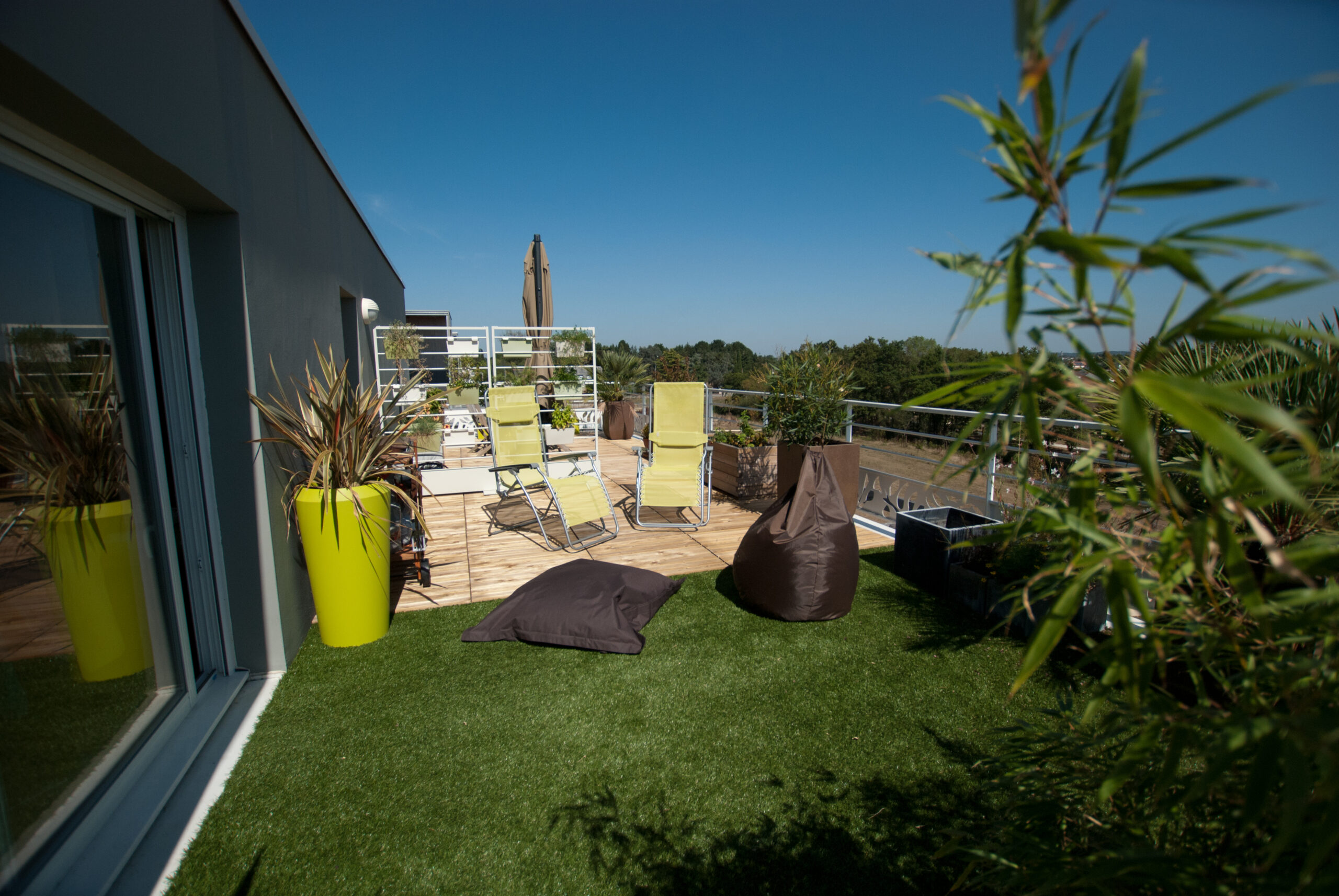 gazon synthétique sur terrasse, séparation en deux espaces distinct, plantes et pots, chamaerops